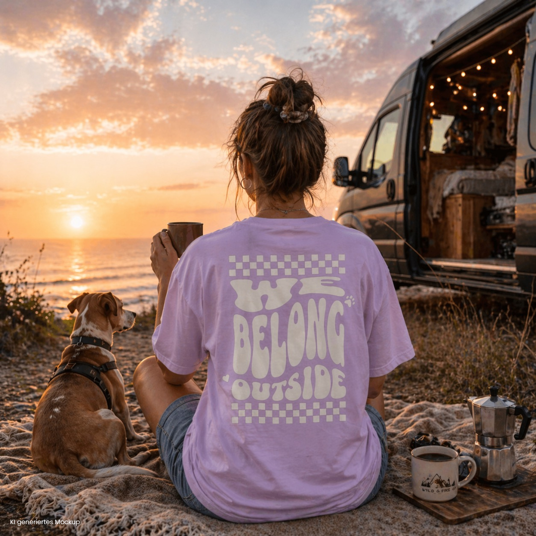 Person sitzt am Strand beim Sonnenuntergang neben Camper und Hund und trägt orchidfarbenes „we belong outside“ T Shirt, ideal für Vanlife und Camping