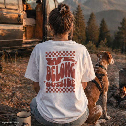 Person sitzt vor Camper mit Hund und trägt T Shirt „we belong outside“, perfekt für Camping, Vanlife und Outdoor mit Hund